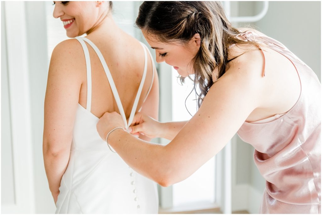 Burnaby Vancouver Wedding bridesmaid buttoning the bride's dress