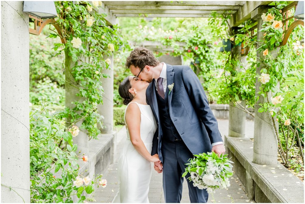 Burnaby Vancouver Wedding Bride and Groom kissing under arbour at the UBC Rose Garden