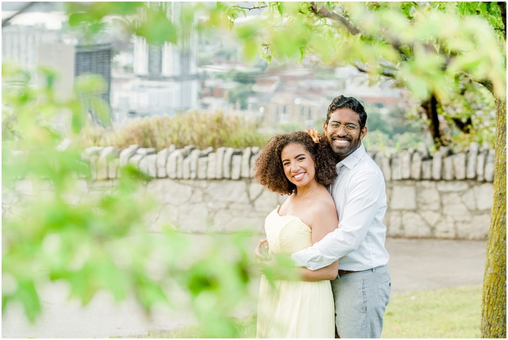 Sam Lawrence Park Hamilton Engagement Session couple hugging and laughing in the trees with city behind them