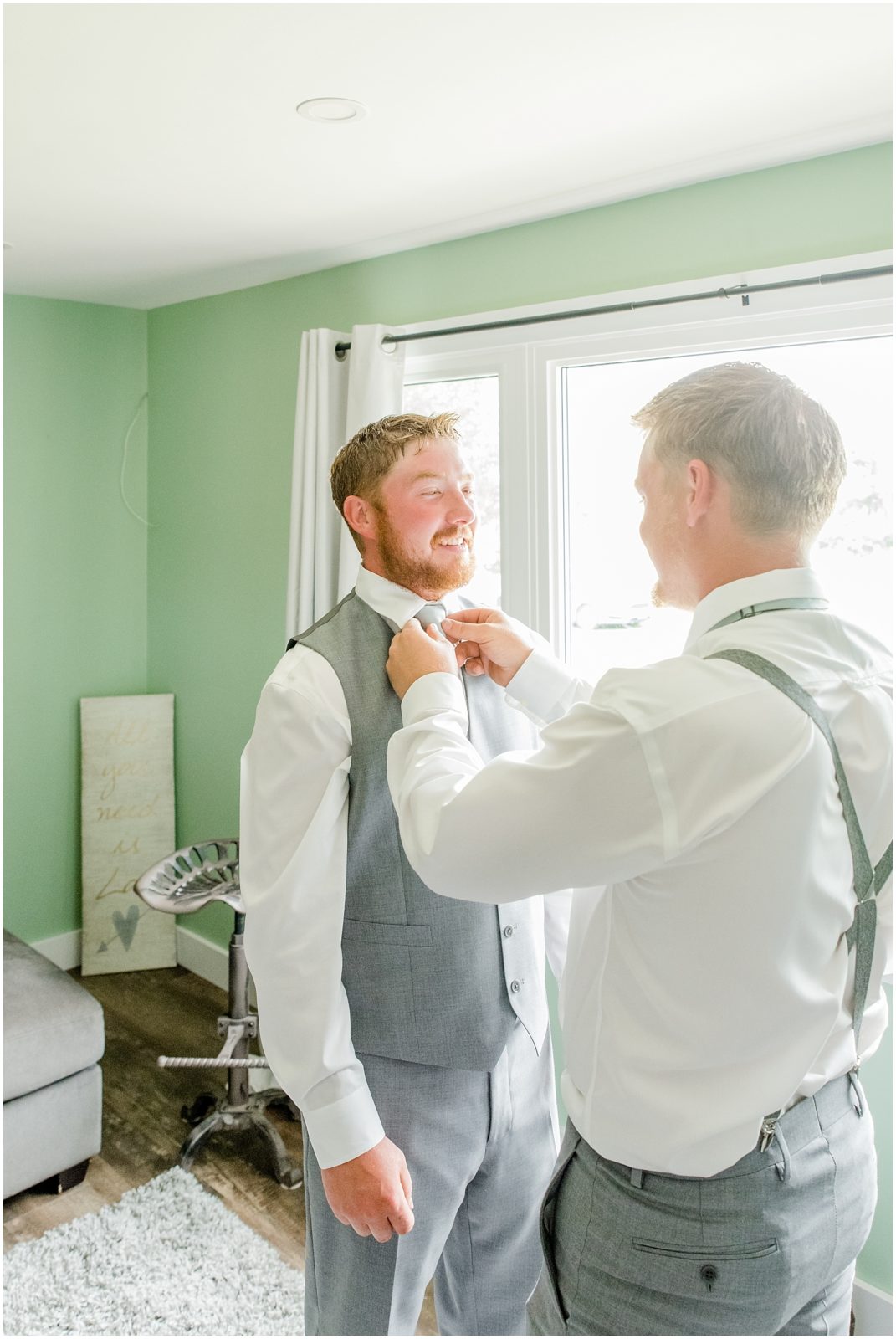 Princeton backyard wedding groomsman helping groom putting on tie