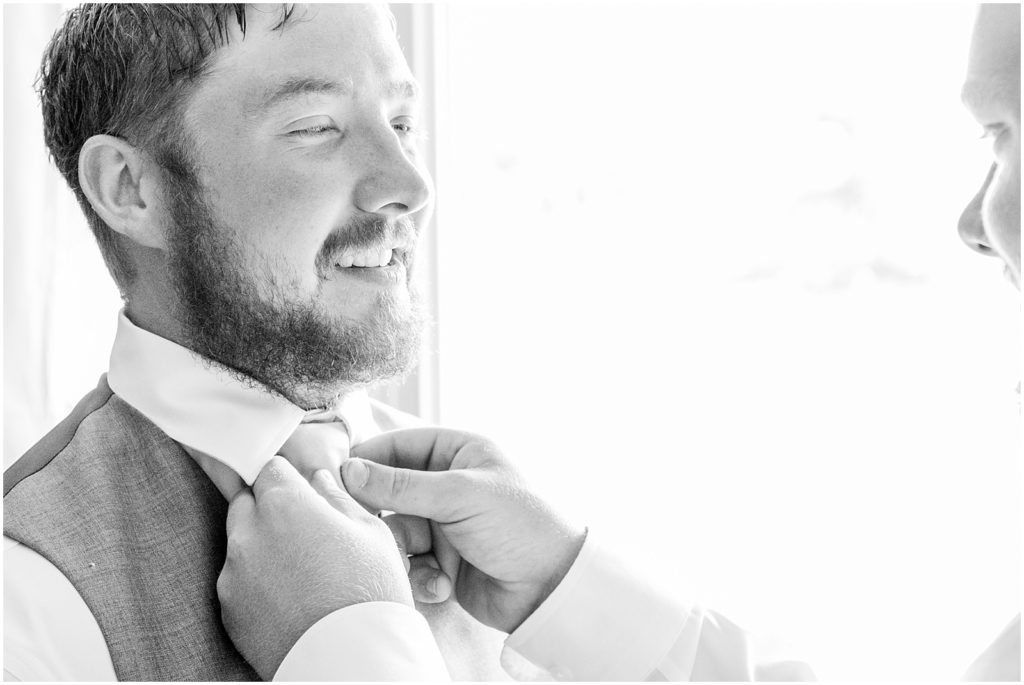 Princeton backyard wedding closeup of groom's tie being adjusted by groomsman