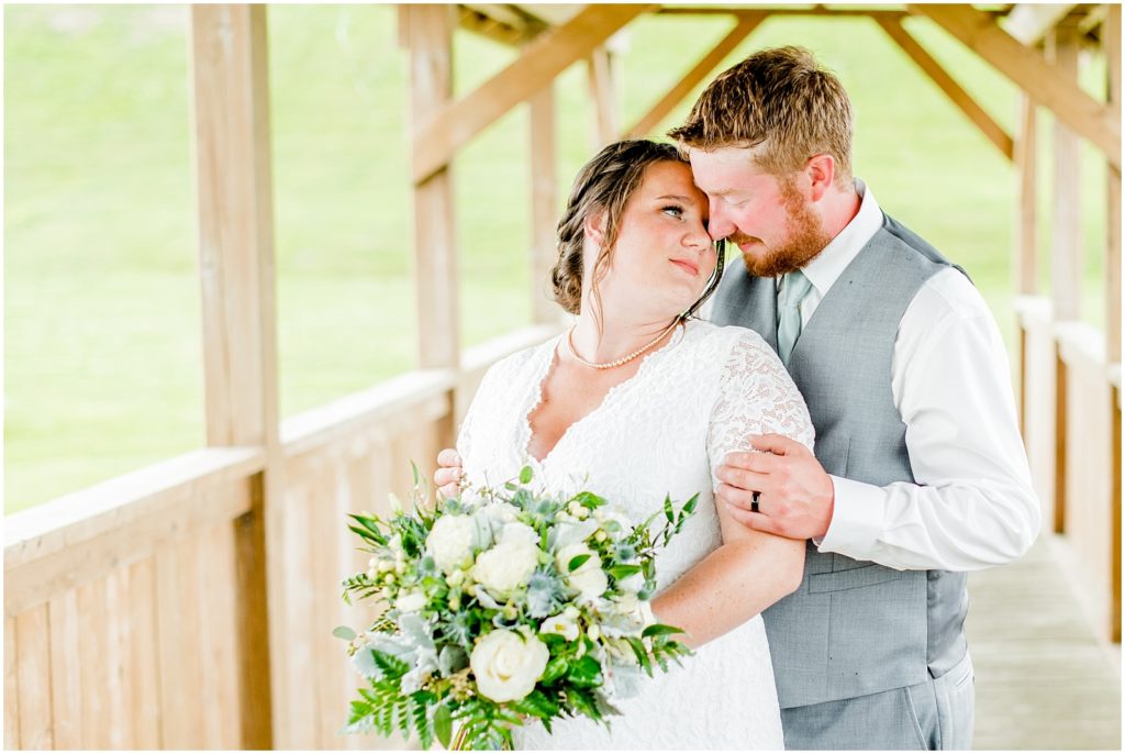 Princeton backyard wedding bride and groom nuzzle on covered country bridge