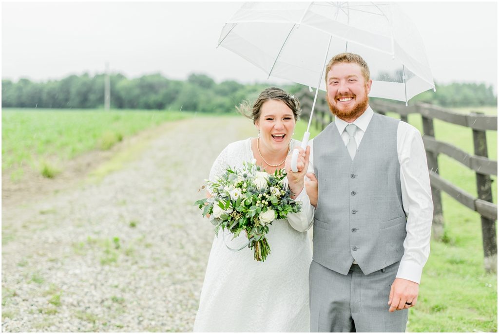 Princeton backyard wedding bride and groom laughing under a clear umbrella in the rain