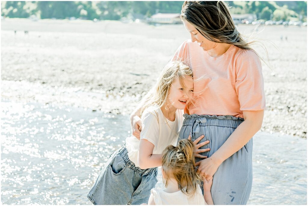 Saint Martins Portrait Session mom and daughters laughing and hugging on the shoreline