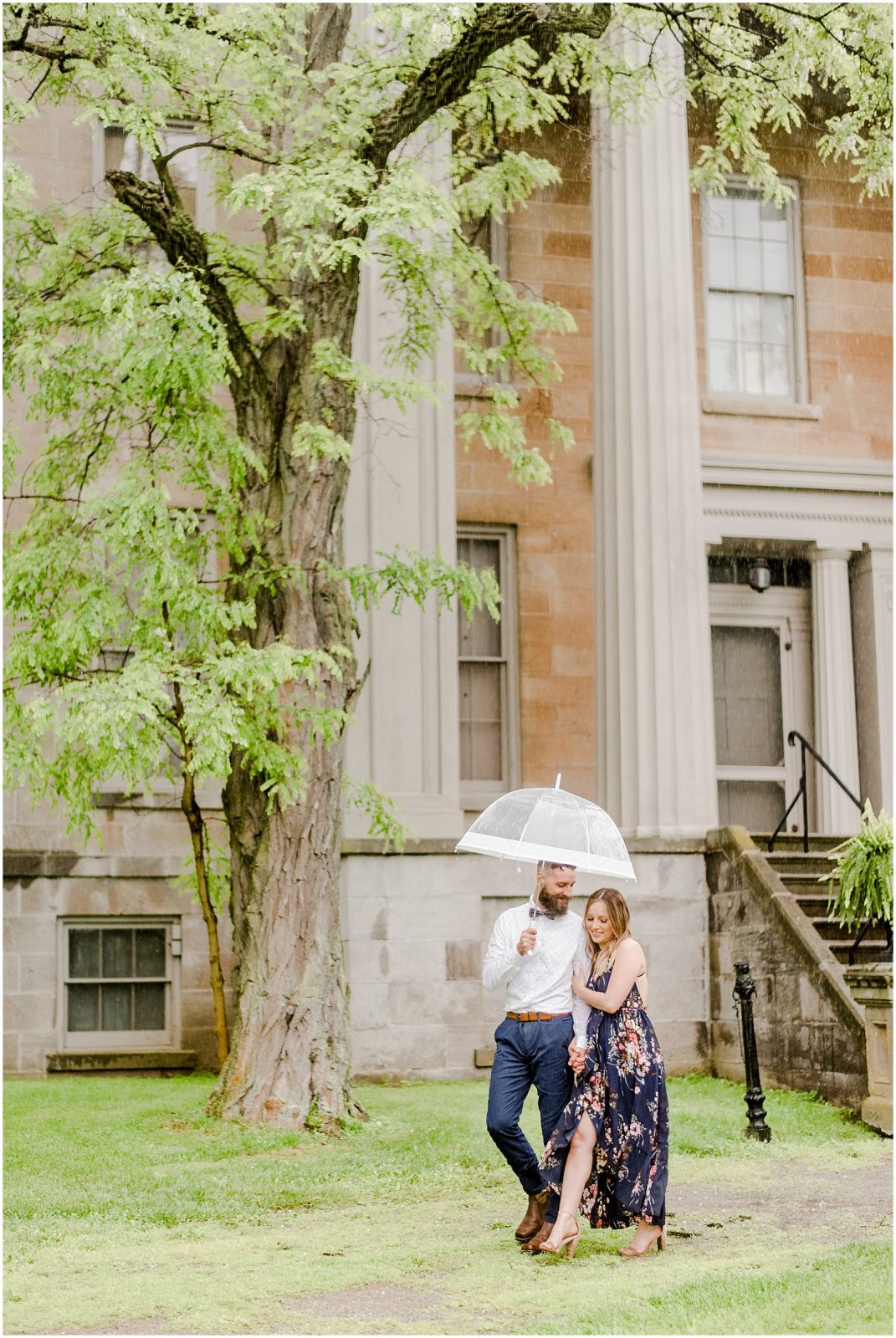 Couple standing in front of steps with umbrellas at Ruthven Park
