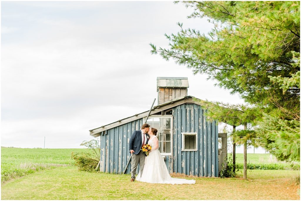 St. Mary's Countryside Wedding bride and groom kissing in front of shed