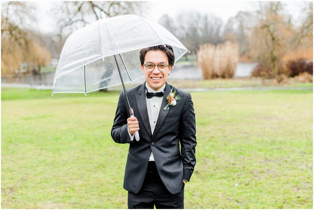 burnaby vancouver wedding groom standing holding umbrella at Trout Lake