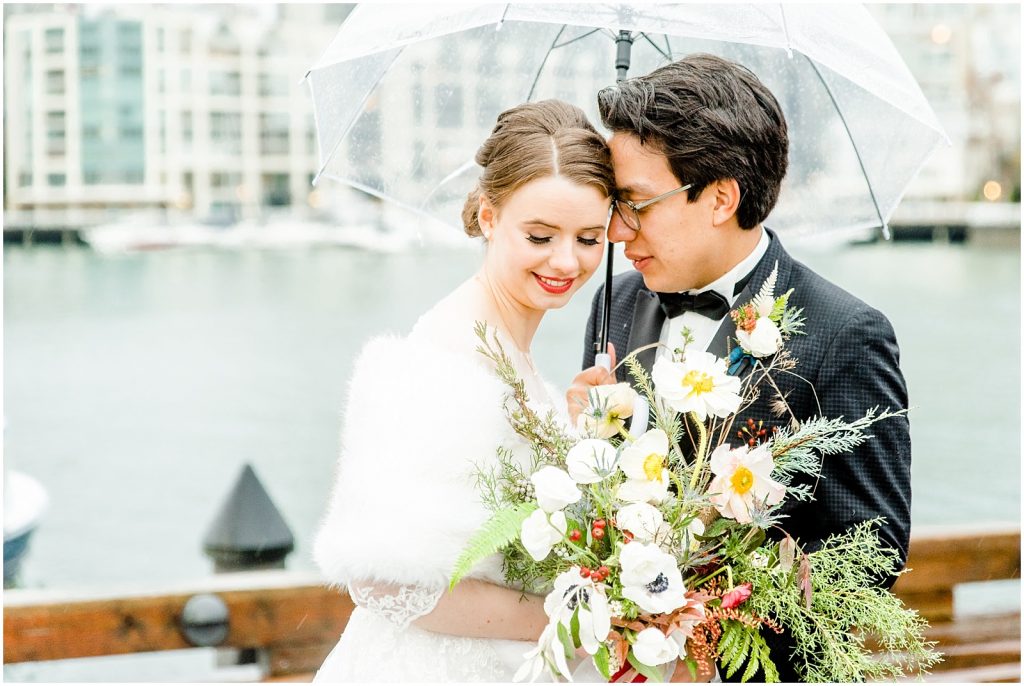 burnaby vancouver wedding Bride and Groom snuggling under umbrella at Granville Island